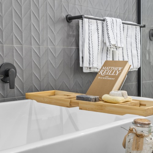 grey tiled feature wall and white bath with wooden caddy